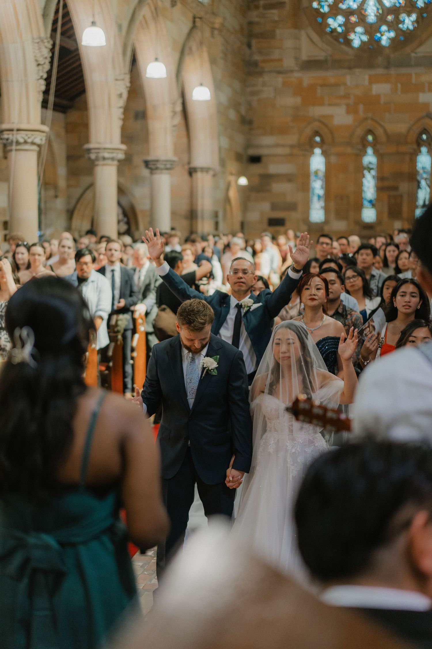 Wedding guests raise their hands in celebration during a joyous church ceremony.