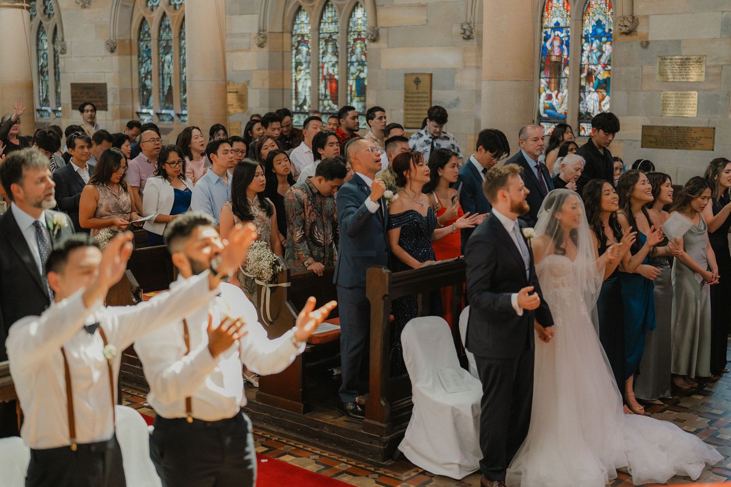 Wedding guests and newlyweds celebrate during a joyous ceremony in a historic stone church.