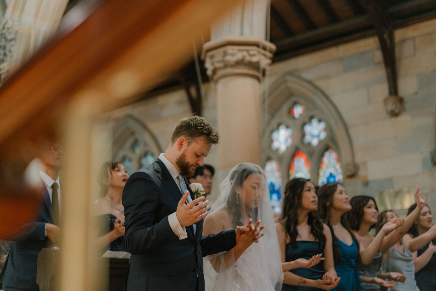 Wedding guests using phones during a celebration in a historic stone church interior.