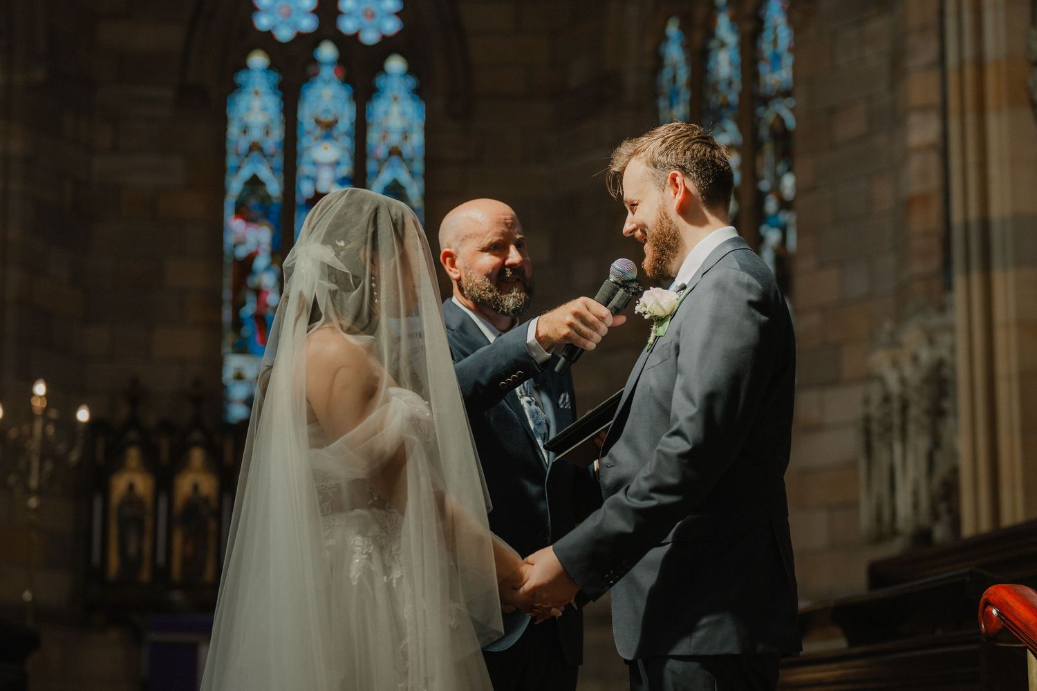 A wedding ceremony taking place in a grand cathedral with stained glass windows.
