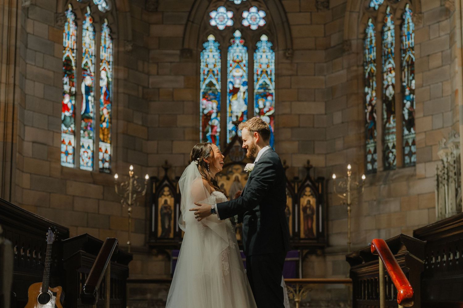 A wedding ceremony in a historic stone cathedral with stained glass windows and arched architecture.
