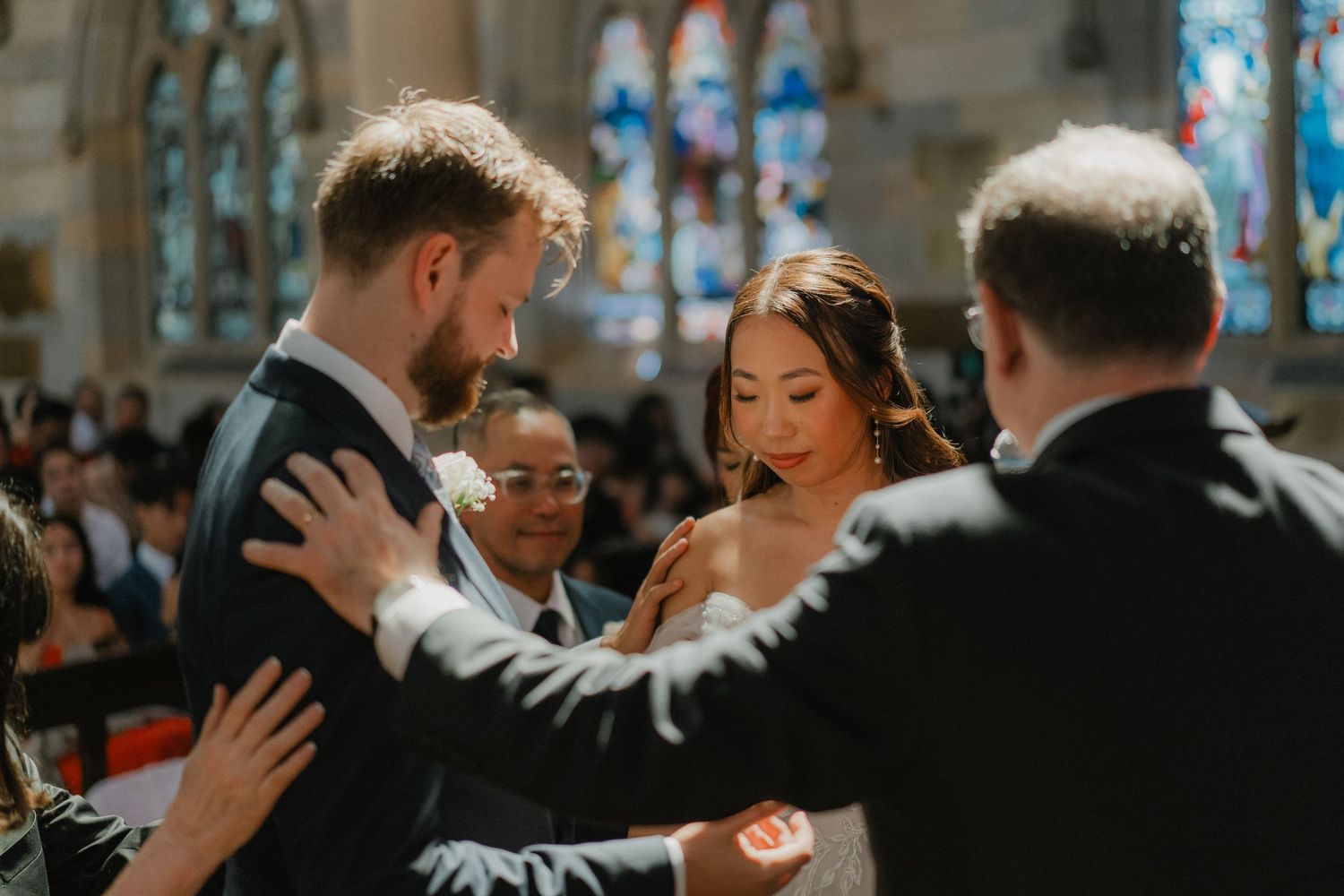 Emotional wedding ceremony moment in a church with beautiful stained glass windows in the background.