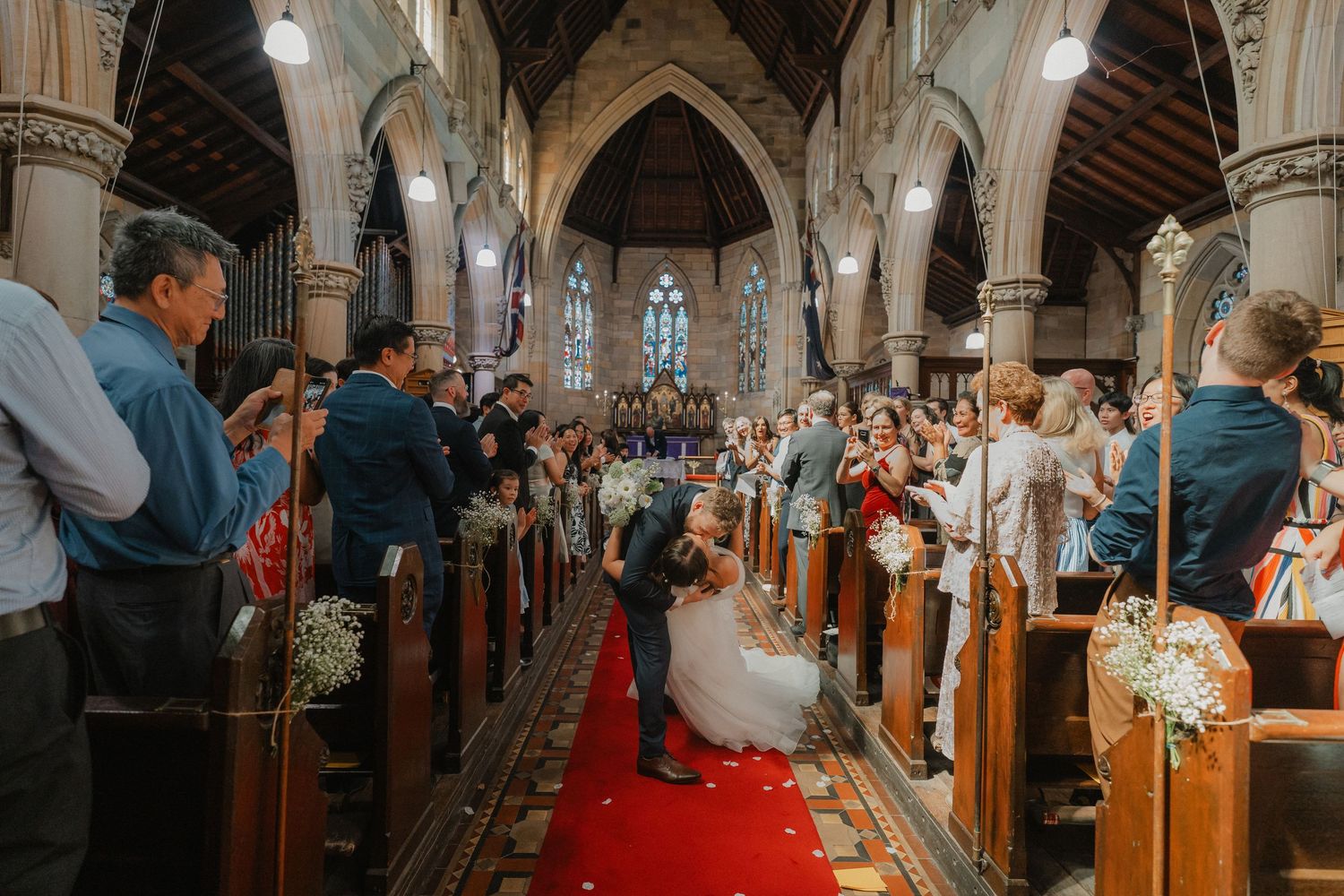 Wedding ceremony in a grand cathedral with red carpet aisle and floral decorations.