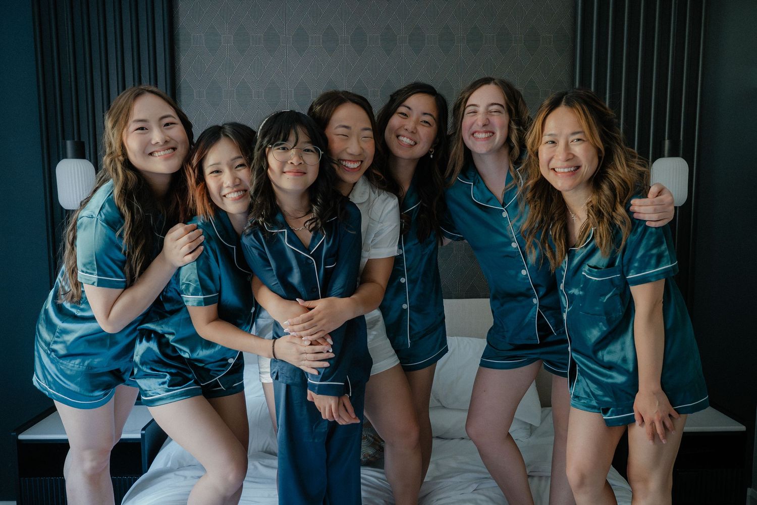 Bridesmaids wearing coordinated blue robes share laughter during morning preparations.