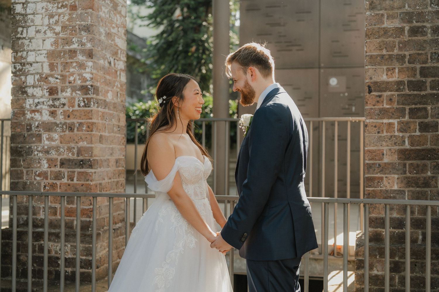An elegant outdoor wedding portrait against a rustic brick backdrop.