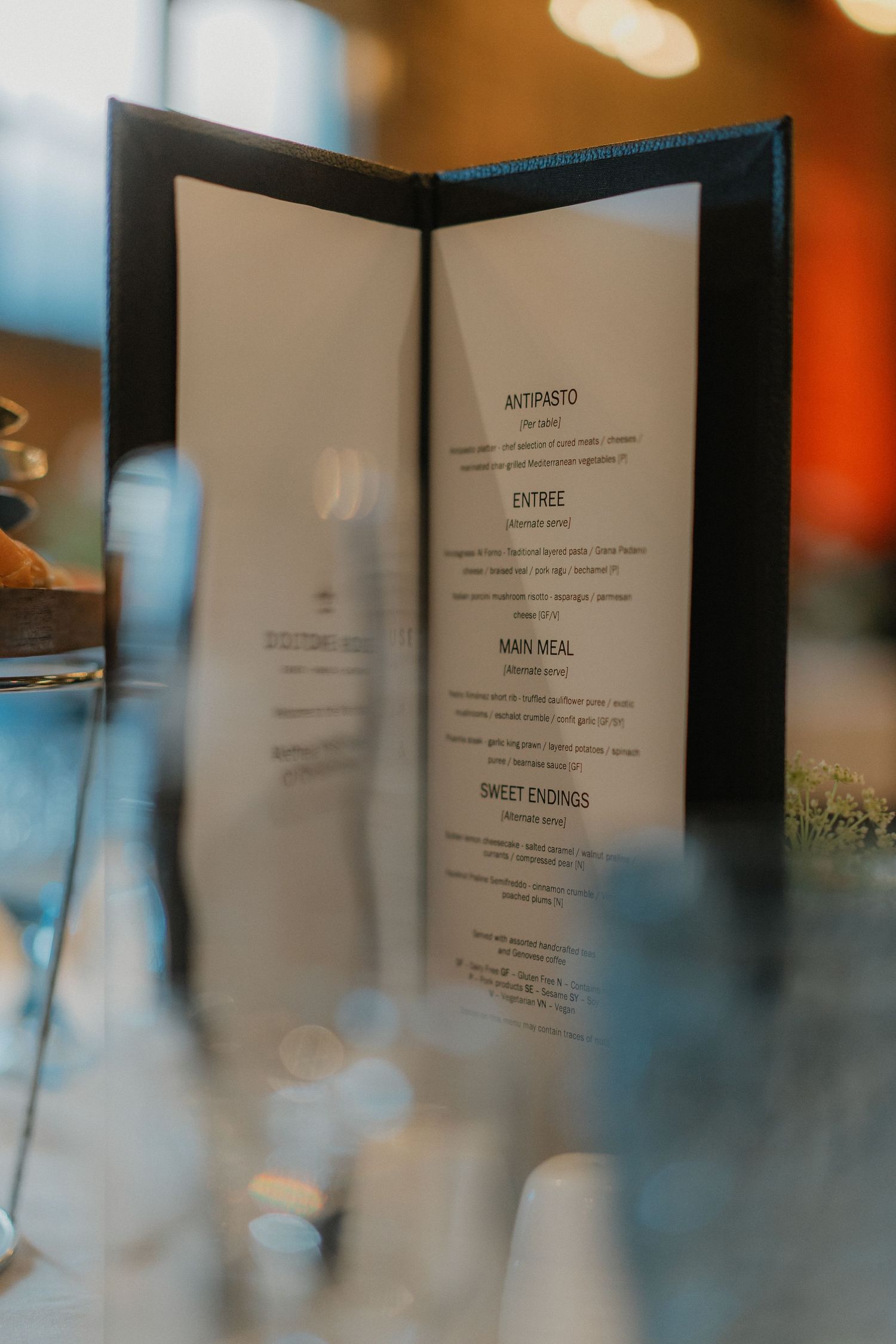 Restaurant menu displayed in an elegant black leather holder with soft bokeh background.