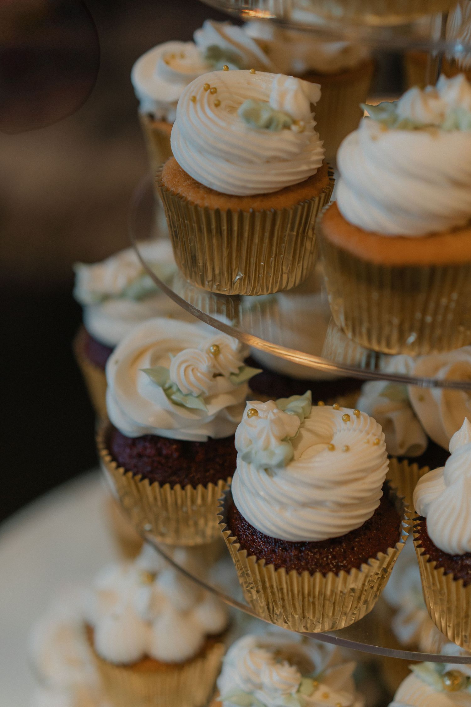 Wedding cupcakes with white frosting arranged beautifully in gold foil liners.