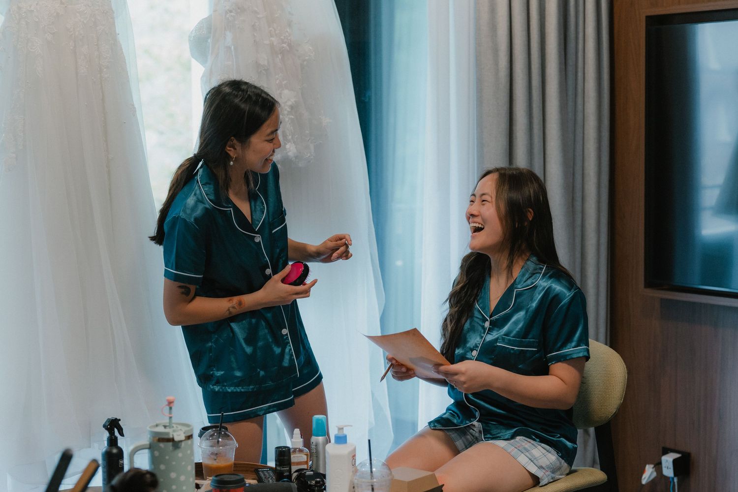 Wedding party getting ready in hotel room with blue robes and natural lighting.