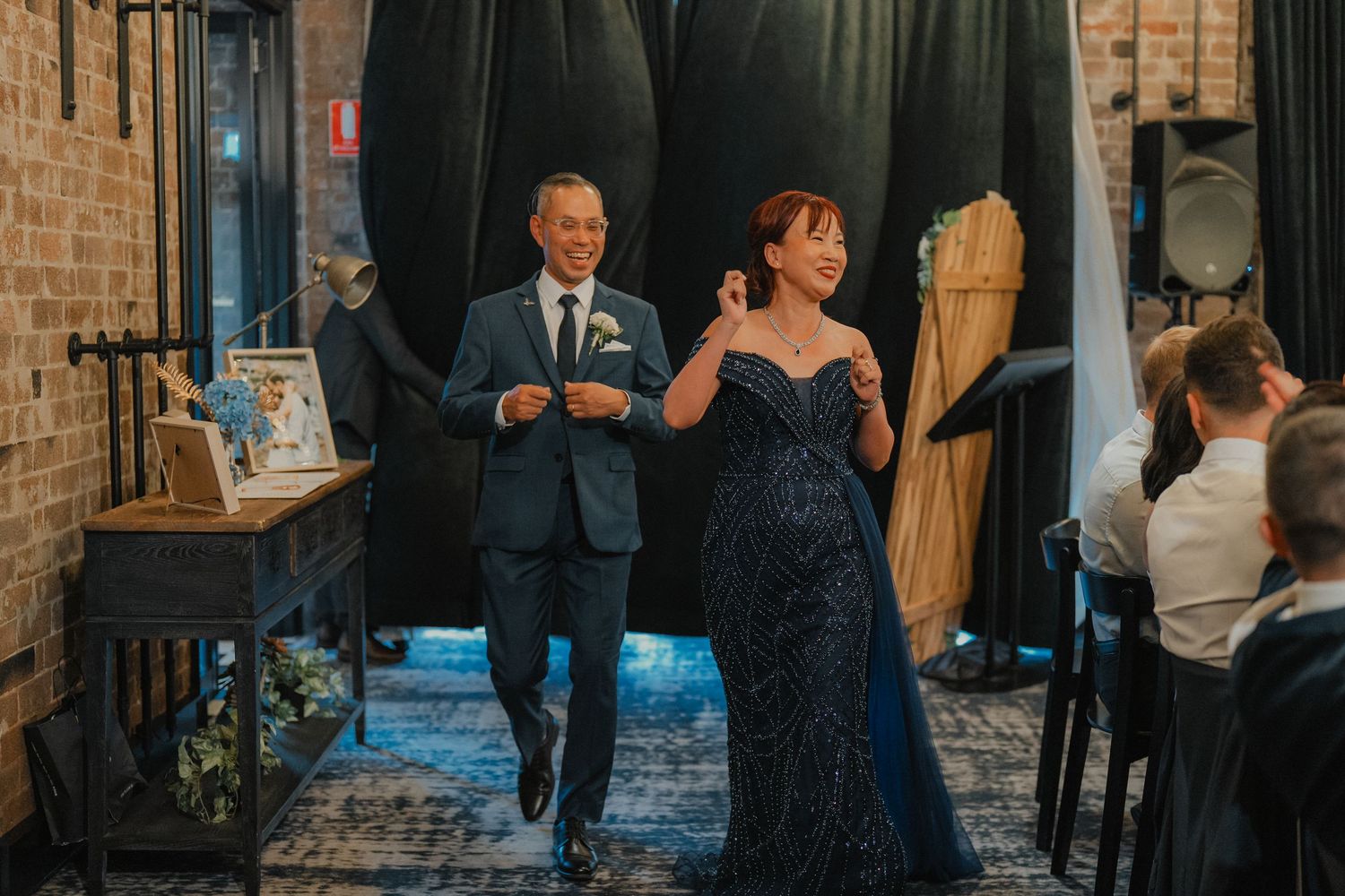 A couple makes their entrance during a wedding reception in a rustic brick venue.