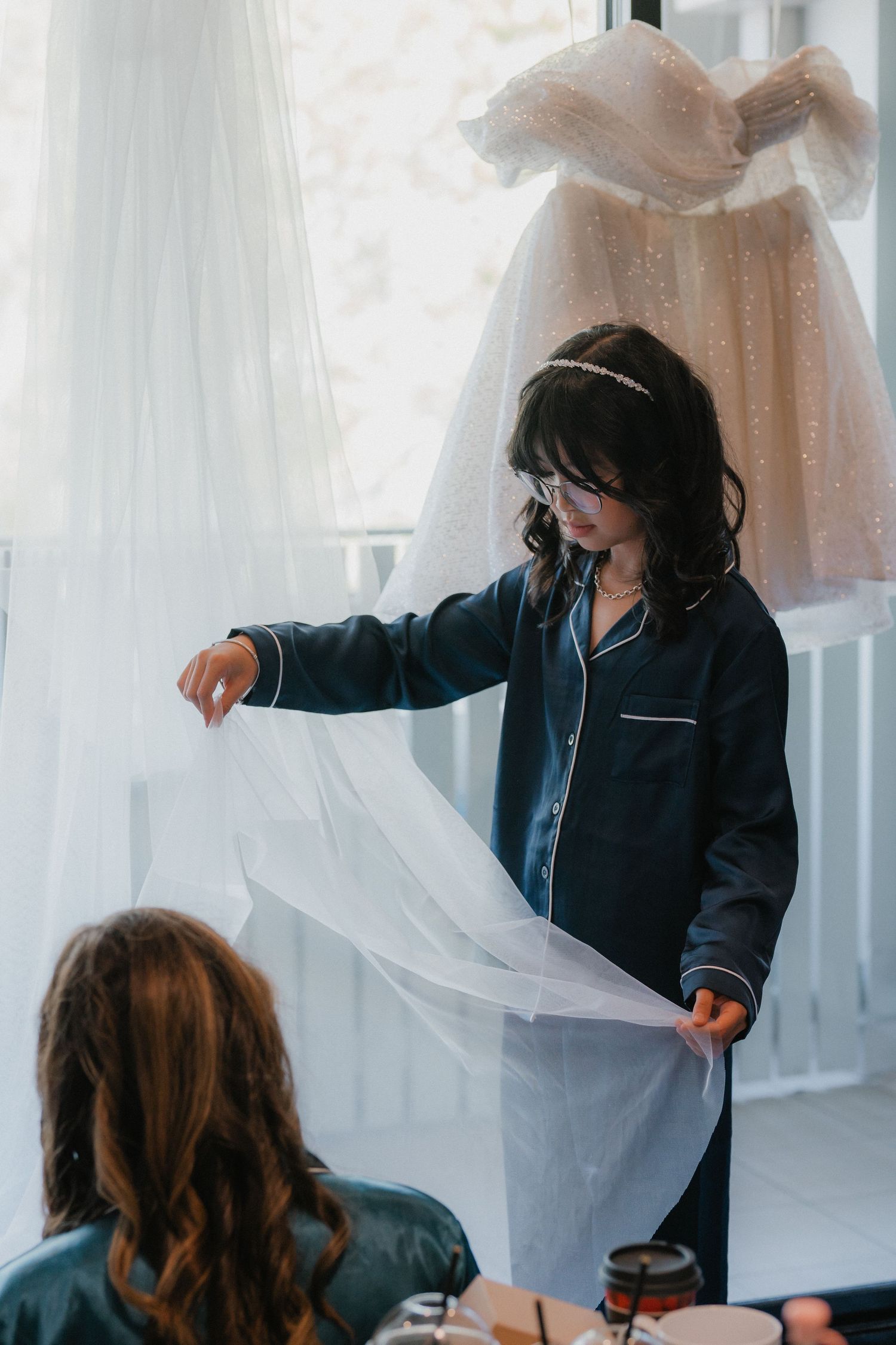 Getting ready scene shows bridesmaids in matching navy pajamas helping with wedding preparations.