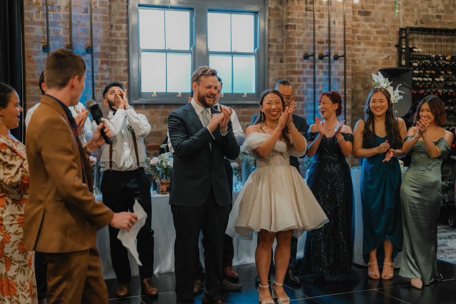 Wedding celebration in an industrial brick venue with blue-lit windows and dancing guests.