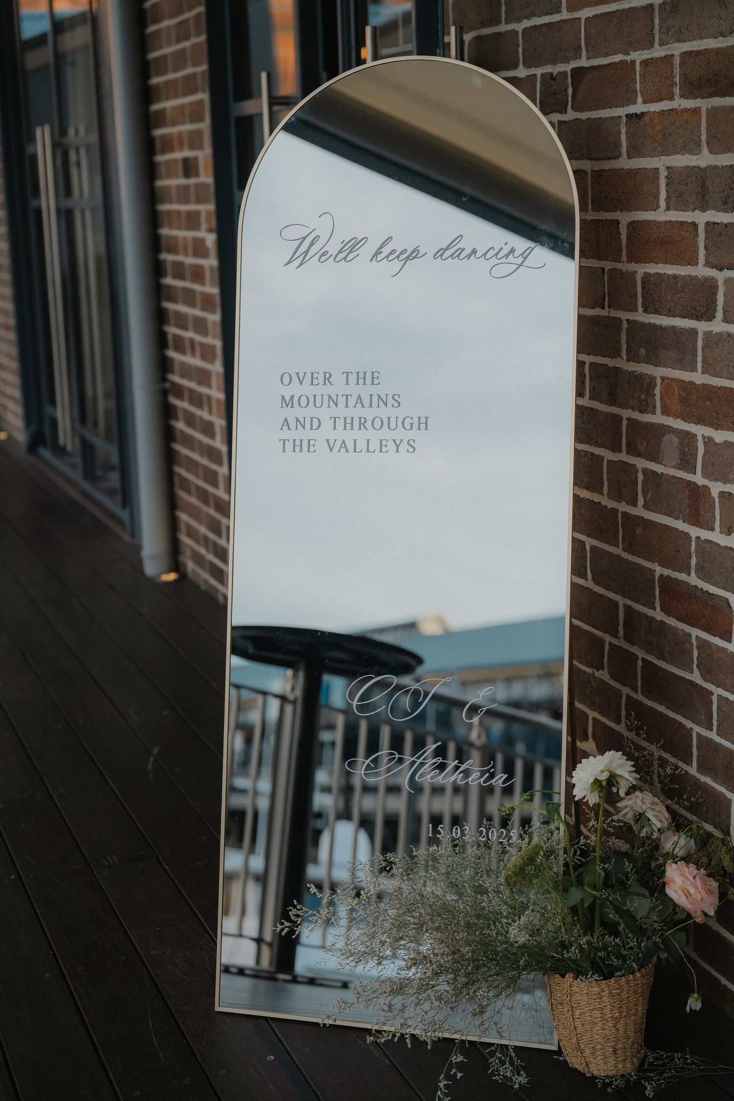 Rustic brick wall decor with framed artwork and text displaying 'Over the mountains and through the valleys'.