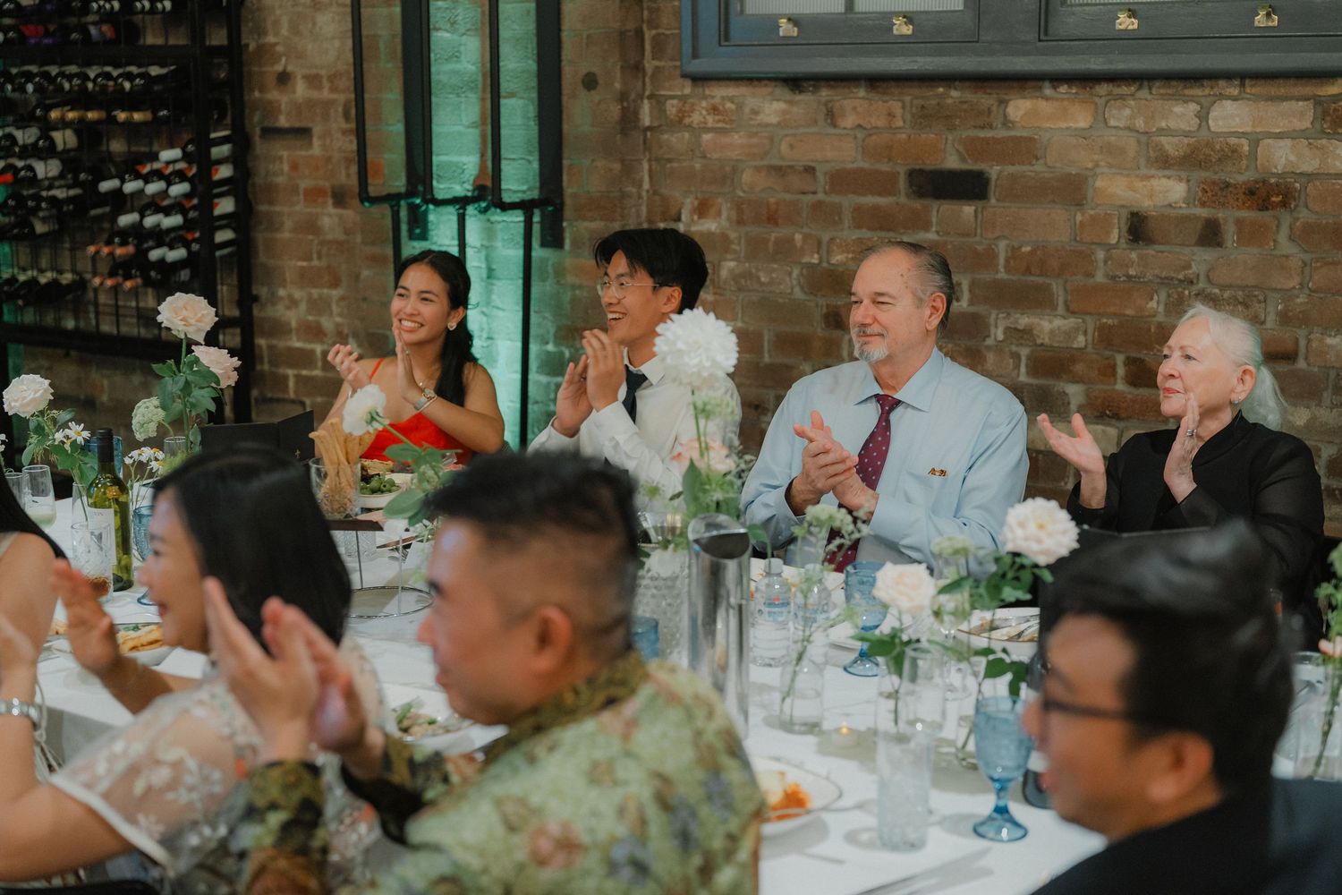 Elegant wedding reception table setup with white flowers and table settings in industrial brick venue.