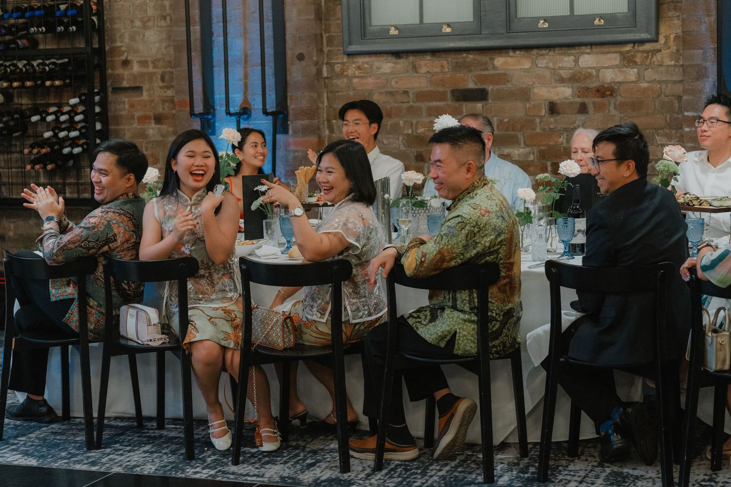 A group of guests sitting at a bar counter enjoying drinks and conversation at a social gathering.