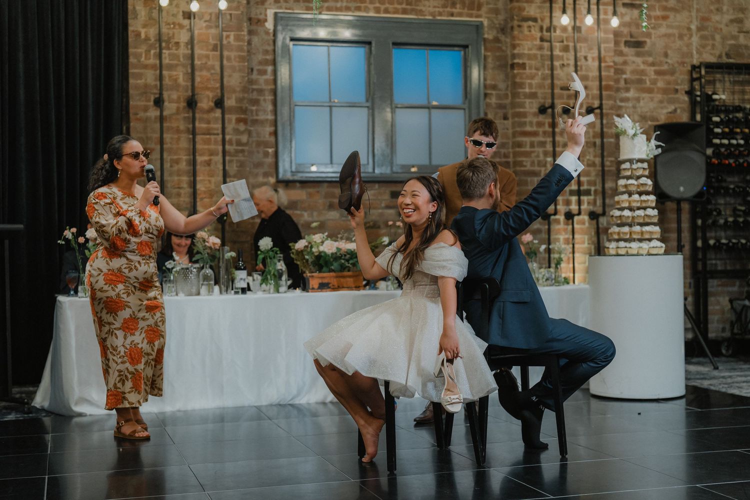 Guests dancing and celebrating at a wedding reception in an industrial brick venue.