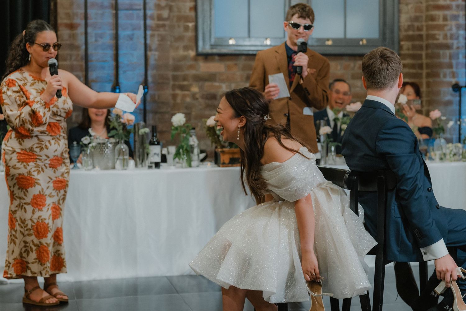 Wedding reception venue decorated with white linens and floral centerpieces.