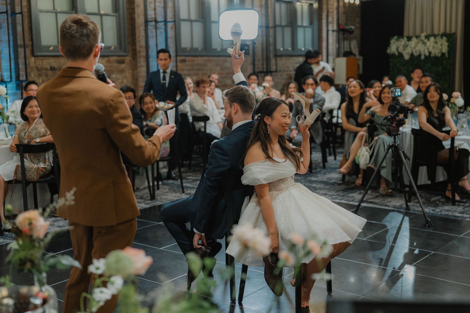 Wedding guests dancing and celebrating on dance floor in industrial-style venue.