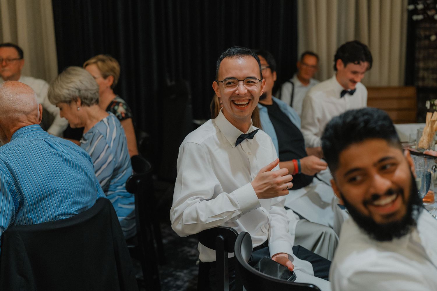 Wedding reception guests enjoying themselves at dining tables.