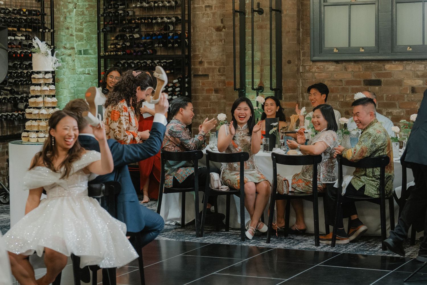 Wedding celebration with guests cheering and clapping at an industrial-style reception venue.
