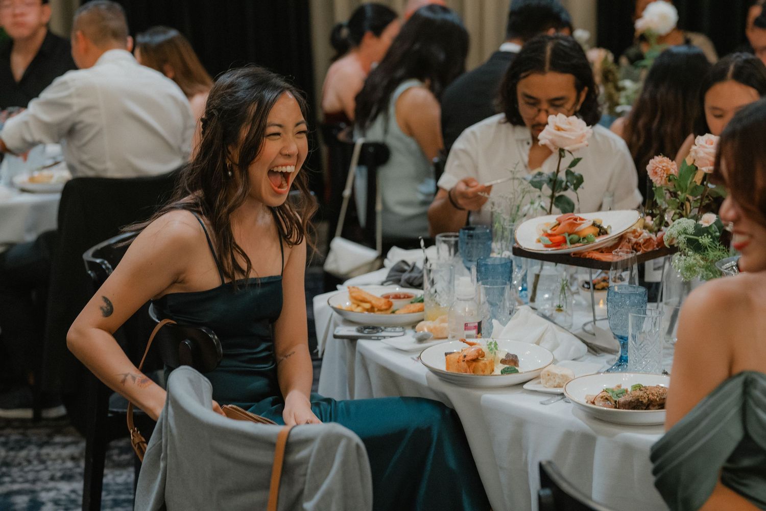 A candid reception photo shows guests seated at round tables enjoying dinner and conversation in an elegant indoor venue.