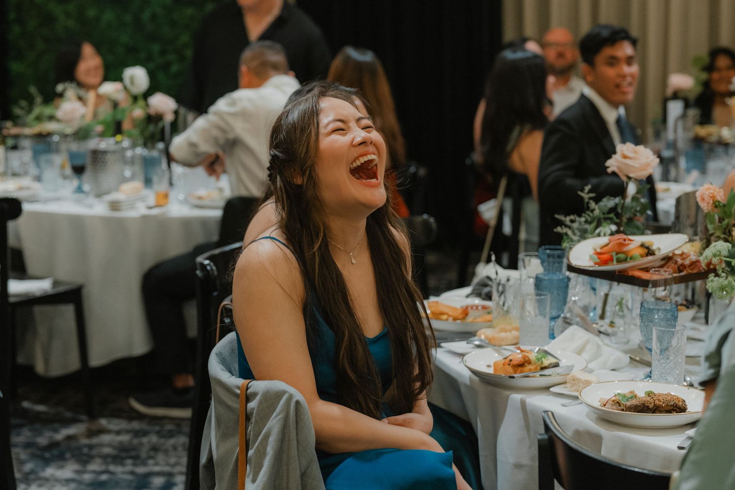 Wedding guests enjoying a lively moment of laughter and celebration at an elegant reception dinner.