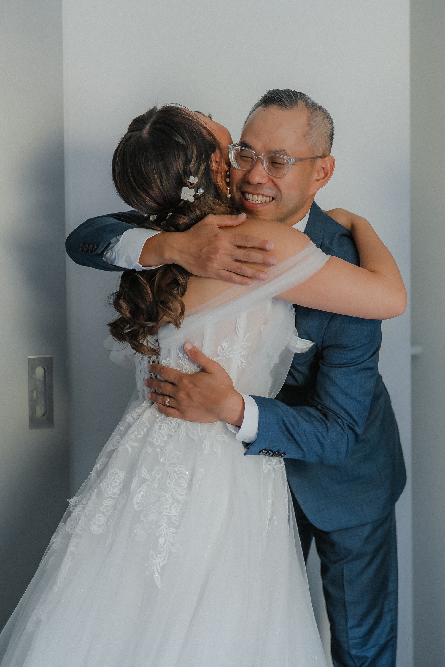 Emotional wedding day embrace between family members in formal attire.