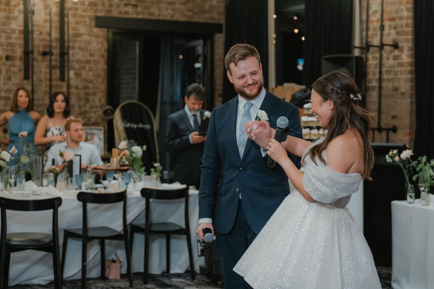 Wedding celebration in a rustic brick venue with guests mingling during reception festivities.