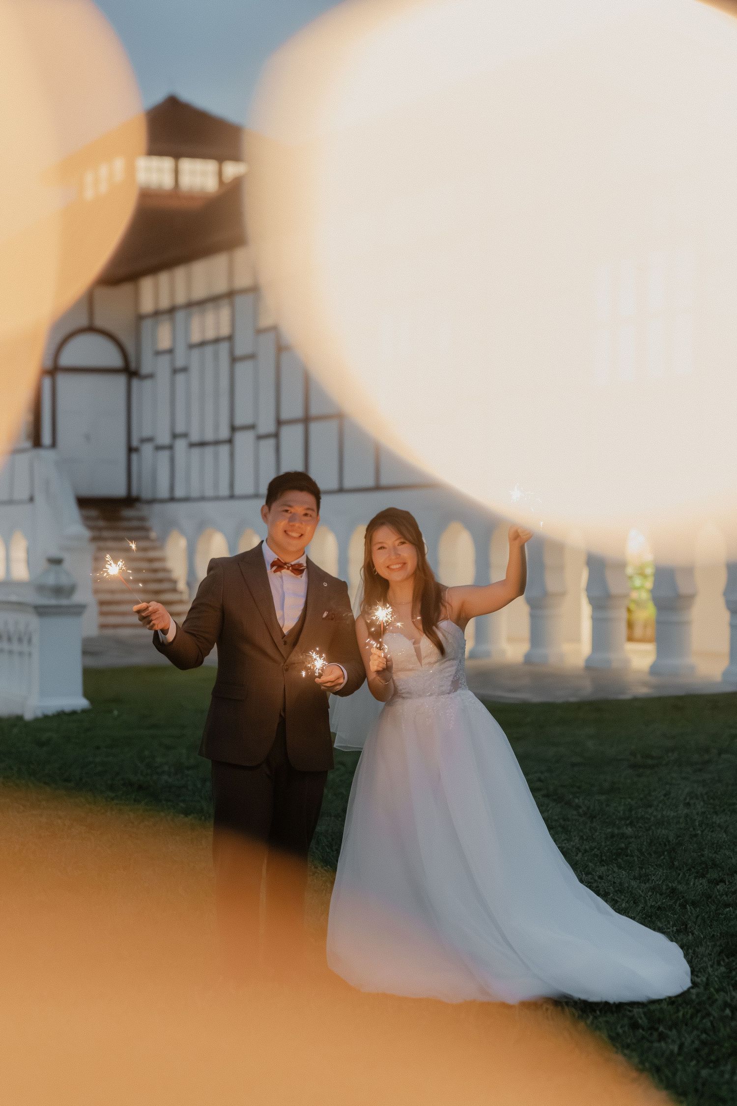 Dreamy sunset wedding portraits with soft bokeh lights and architectural backdrop.