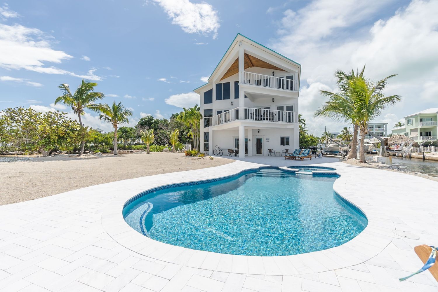 Contemporary beach house with curved swimming pool and palm trees.