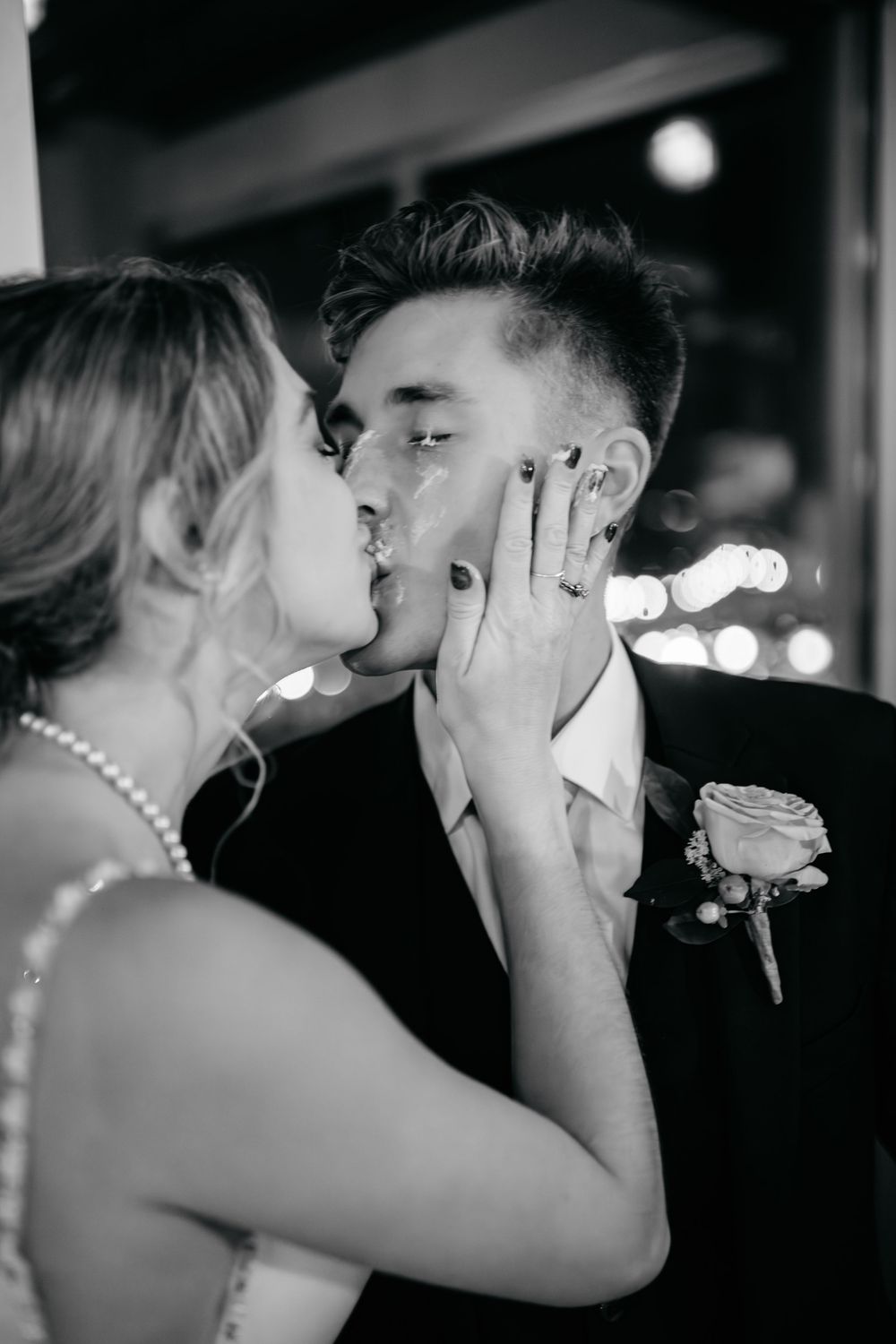 Black and white photo of a bride and groom sharing a romantic first kiss at their wedding reception.