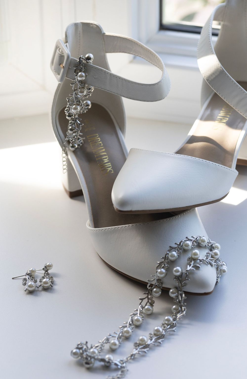 Brides shoes stacked carefully with her jewelry draped on it