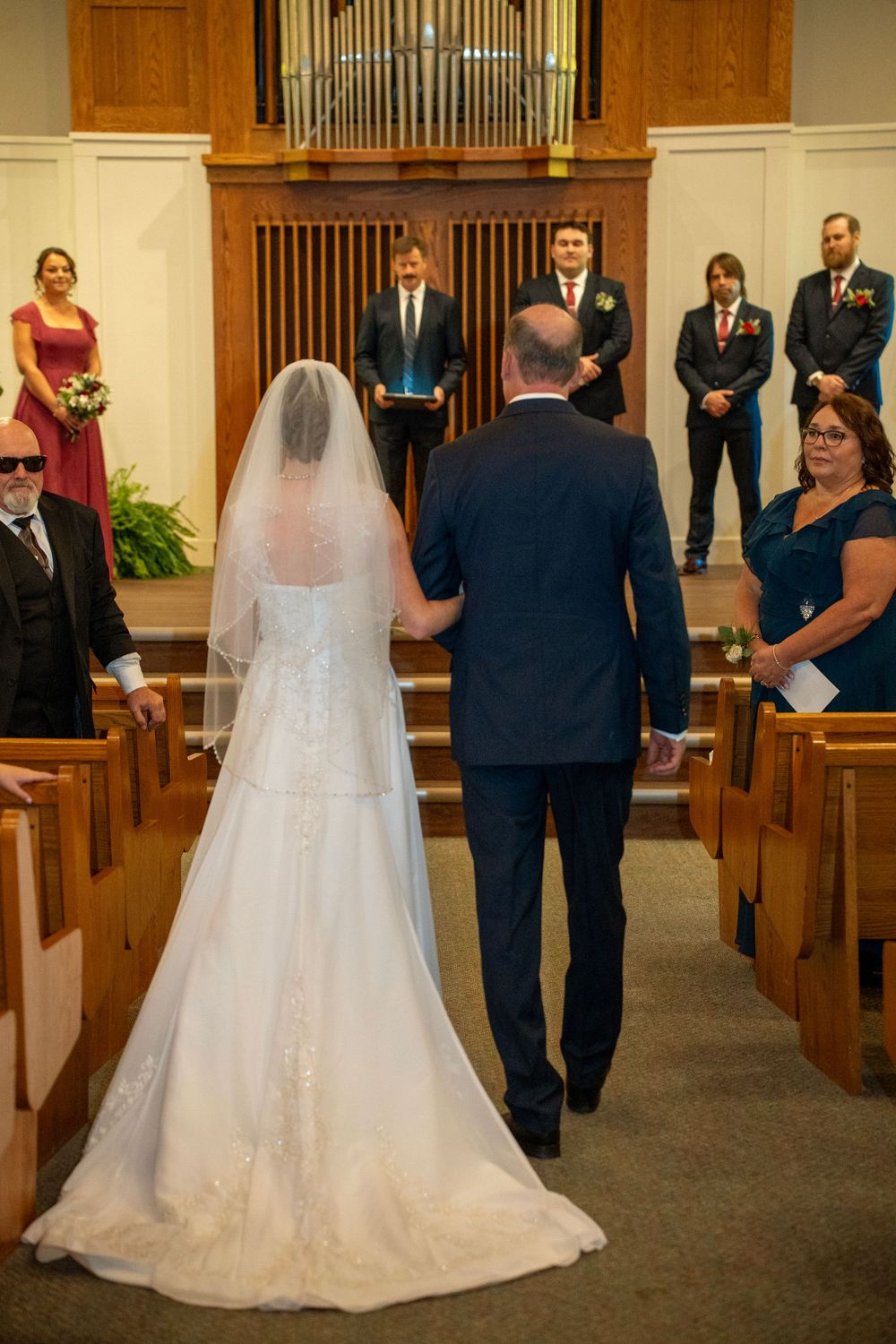 A portrait of a bride and her father walking down the aisle.