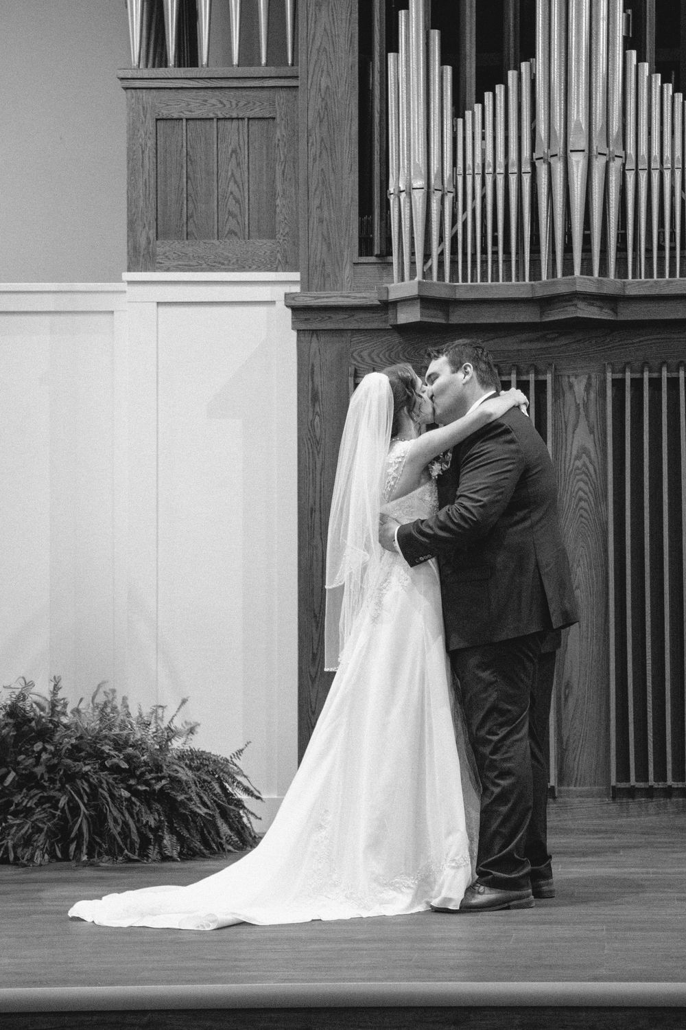 A black and white photo of the first kiss at a wedding ceremony