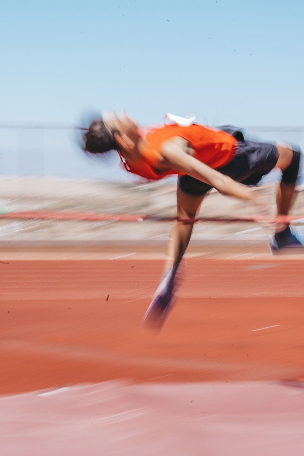 Motion blur captures athletes performing high jumps on red track surface.