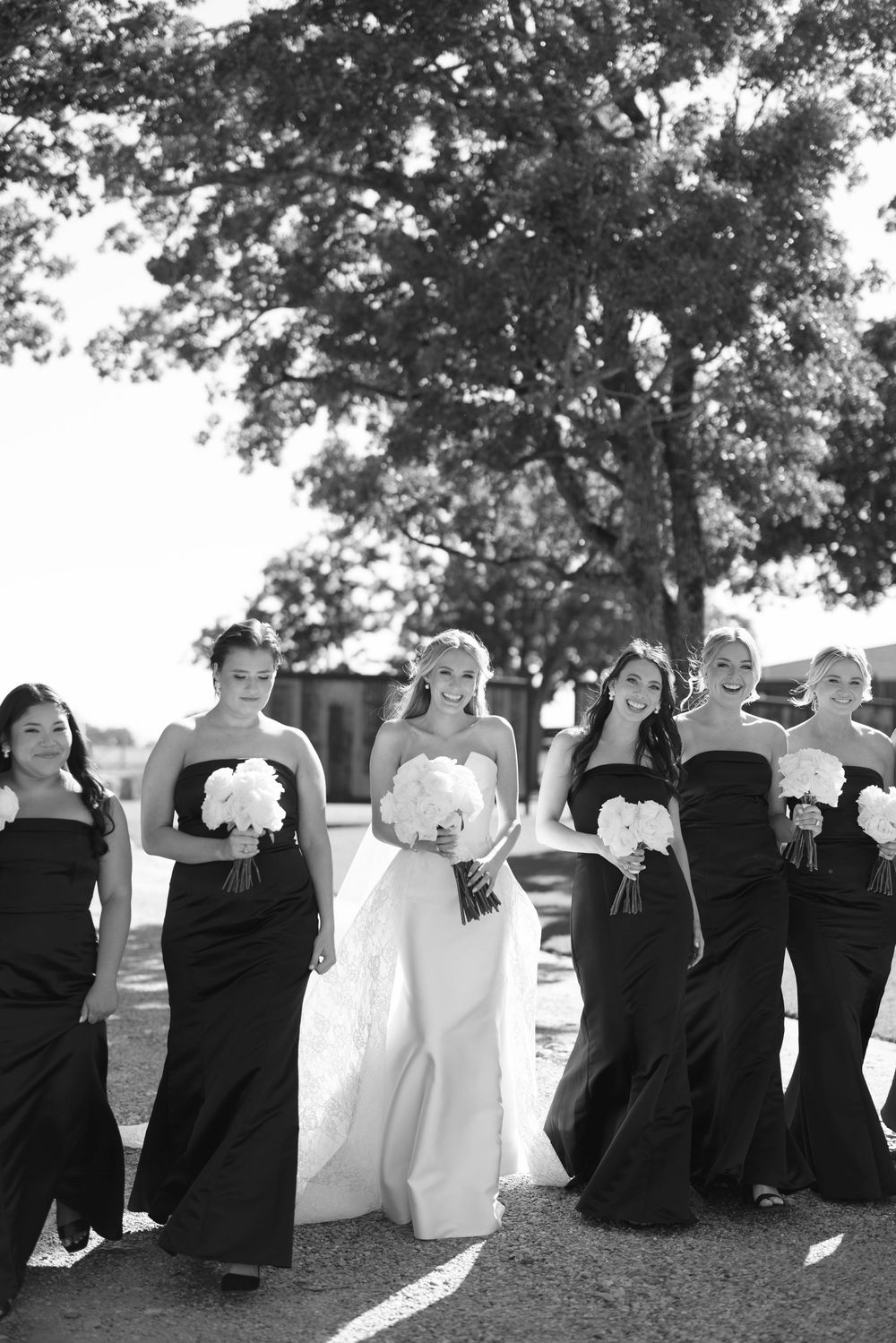 A wedding party lines up with their backs to the camera in a creative outdoor group photo pose.