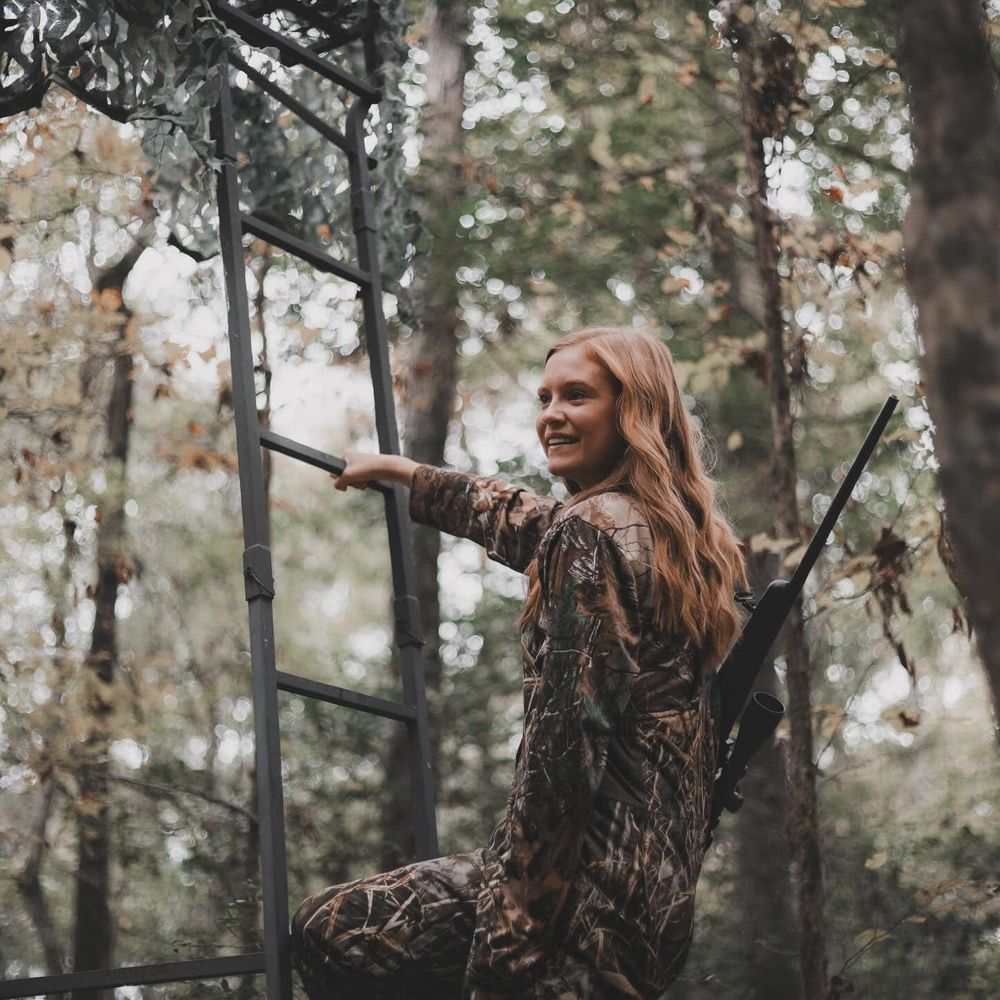 Hunter in camouflage gear climbing into elevated hunting position.