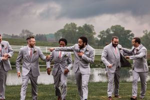 groom and groomsmen walk and laugh with storm clouds in the background at Lingrow Farm wedding
