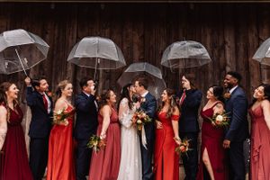 wedding party celebrates kissing newlyweds under umbrellas
