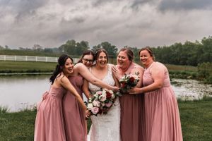bride and bridesmaids hug and laugh with storm clouds in the background at Lingrow Farm wedding
