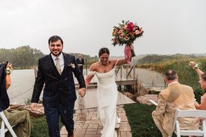 Wedding couple and guests laughing together in scenic outdoor setting during golden hour celebration.