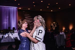 A couple shares an intimate dance under purple lighting at an elegant wedding reception with guests looking on.