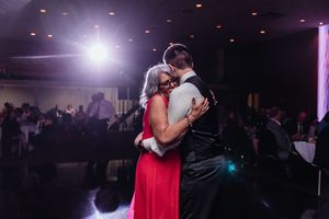 Event guests dance together in a dark reception hall illuminated by pulsing lights and disco effects.