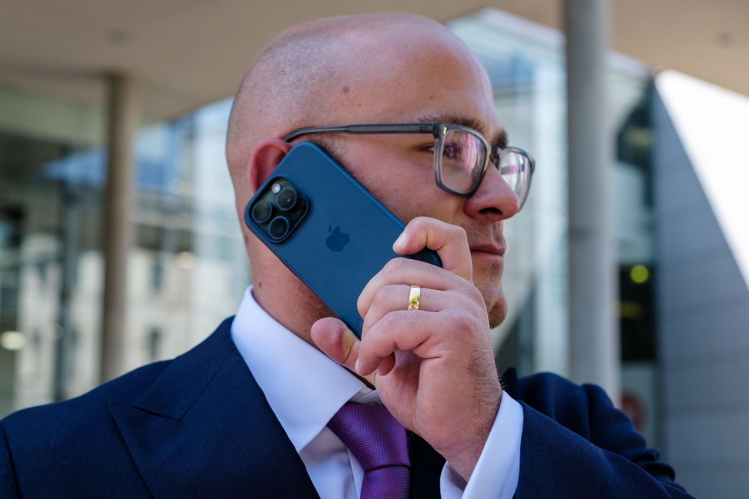Business person holding smartphone to ear while sitting in office setting.
