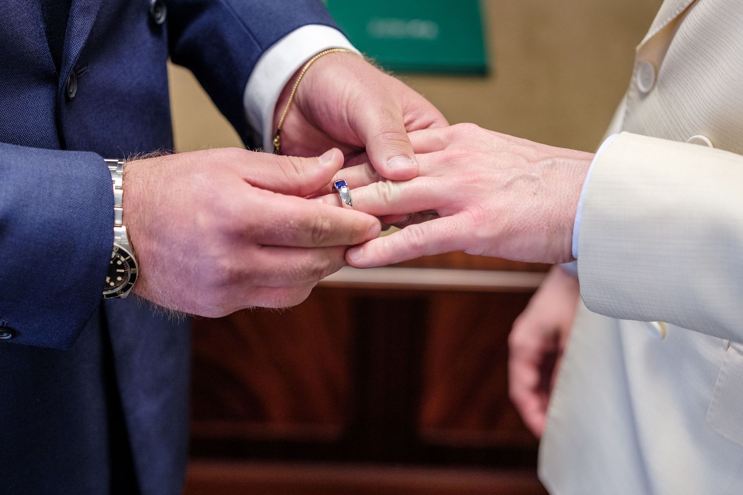 A close-up shot of hands exchanging wedding rings during a marriage ceremony.