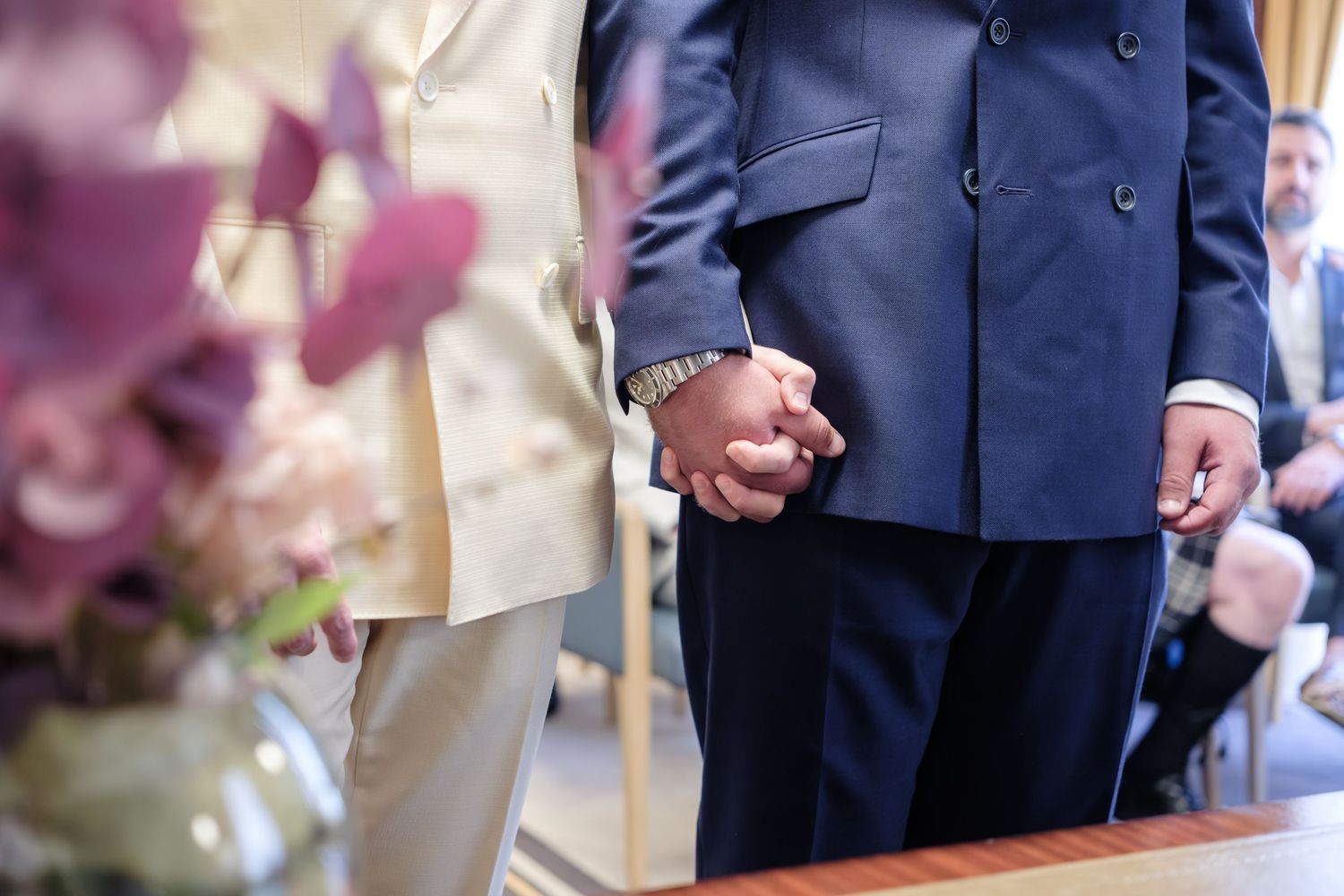 A close-up detail of wedding attire showing formal suits and dress fabrics during a ceremony.