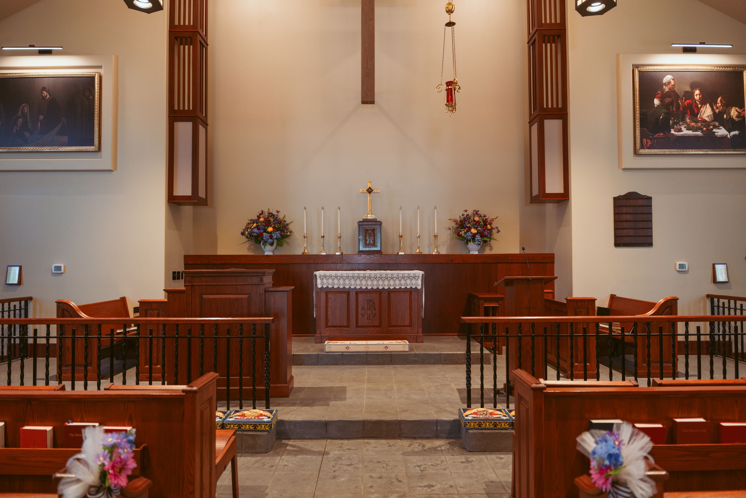 Interior view of church sanctuary with wooden pews, crosses, altar area and warm lighting.