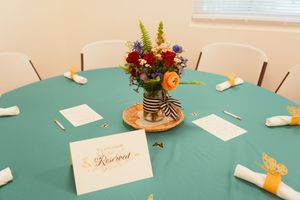 Panoramic sequence of a wedding event table setup with name cards, decor, and florals against a teal tablecloth.