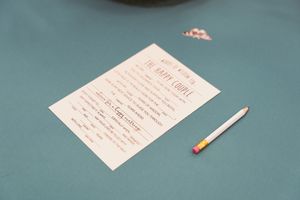 A white paper questionnaire or form lies on a teal surface next to a small pencil.