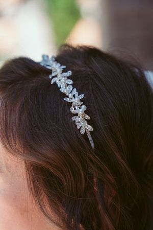 A delicate silver floral headband with crystal embellishments adorns dark brown hair.