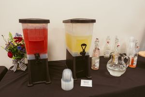 An array of decorative glass bottles, vases, and lighting fixtures displayed on a dark surface against a white wall.